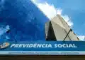 Prédio do INSS com fachada espelhada e placa Previdência Social representando fechamento temporário das agências no Brasil