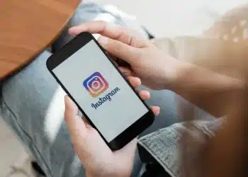 Pessoa segurando smartphone com o logo do Instagram na tela, ilustrando o lançamento do 'Instants'.