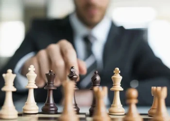 Homem de negócios movimentando peça de xadrez representando tomada de decisão e liderança estratégica