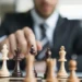 Homem de negócios movimentando peça de xadrez representando tomada de decisão e liderança estratégica