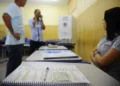 Mesária aguardando enquanto eleitores estão registrando seus votos nas Eleições.