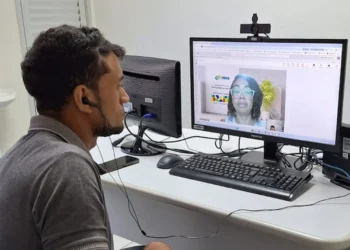 Homem participando de mutirão do INSS para perícia médica, assistindo a uma videoconferência.