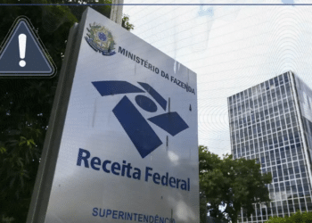 Placa de identificação da Superintendência da Receita Federal do Ministério da Fazenda em frente a edifício comercial, com ícone de alerta amarelo em destaque