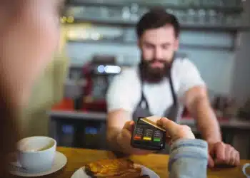 Cliente pagando refeição com cartão de vale-refeição em maquininha de restaurante.