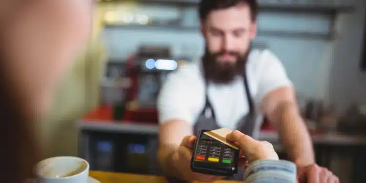 Cliente pagando refeição com cartão de vale-refeição em maquininha de restaurante.