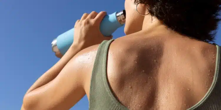 Mulher suando enquanto bebe água representando onda de calor intensa que afeta estados brasileiros