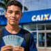 Estudante segura dinheiro em frente a uma agência da Caixa em referência aos pagamentos do Pé-de-Meia de agosto.