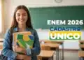 Estudante sorridente segurando cadernos em sala de aula com referência à isenção da taxa do Enem 2026 para participantes do CadÚnico.