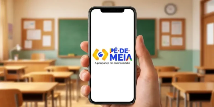 Estudante segurando celular com a conta do programa Pé-de-Meia aberta em sala de aula, representando o alerta do governo sobre o acesso à conta