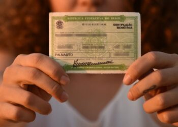 Eleitora segura título eleitoral brasileiro com biometria destacando prazo para regularização antes das eleições.