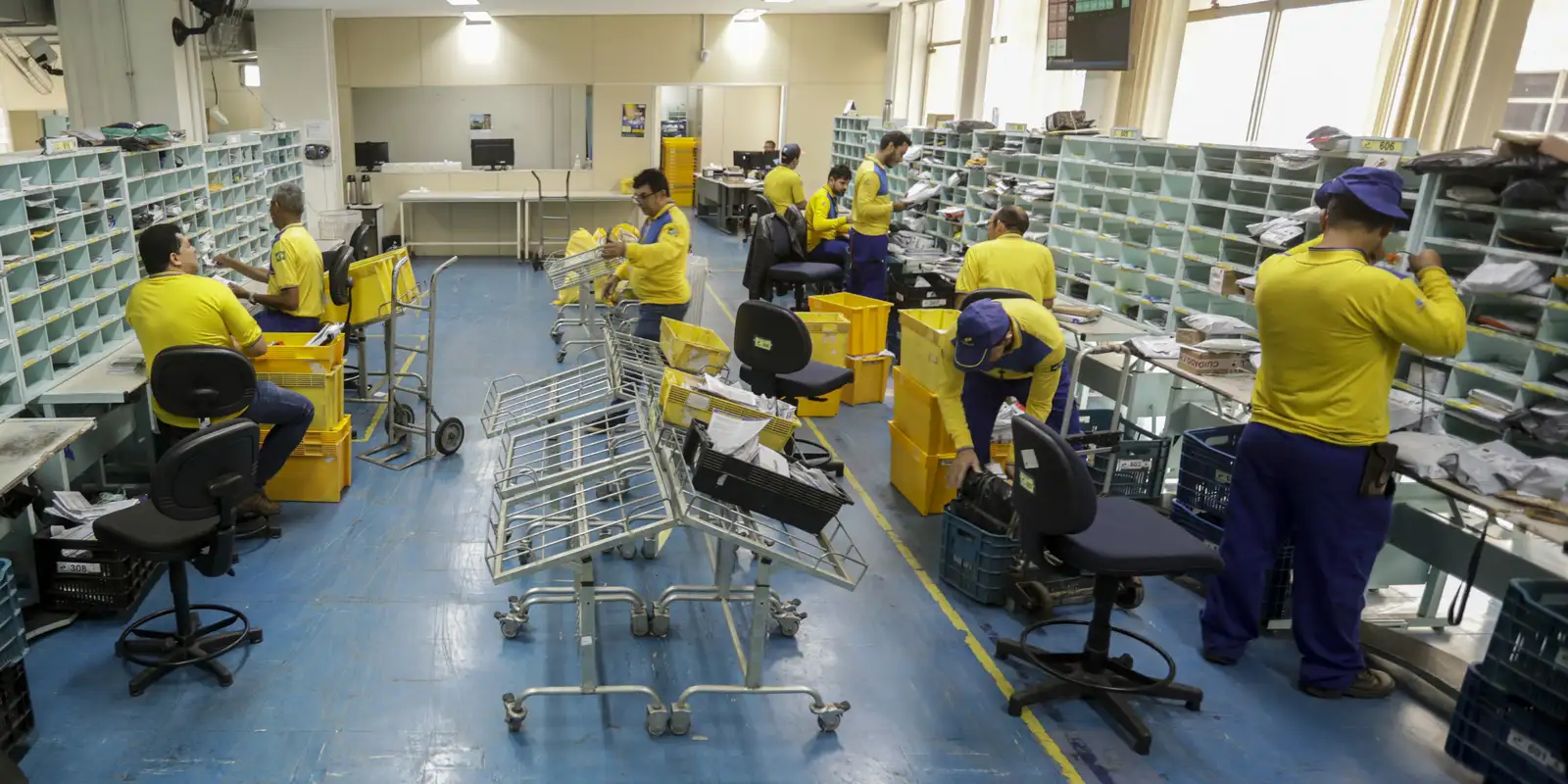 Ambiente interno de uma agência dos Correios, com funcionários organizando pacotes e correspondências para o processo seletivo de 548 vagas no programa Jovem Aprendiz.