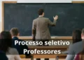 Professor escrevendo em quadro em sala de aula durante processo seletivo público.