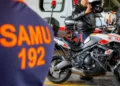 Profissional do SAMU em motolância equipada para atendimento pré-hospitalar , ao lado de uniforme laranja com inscrição SAMU 192.