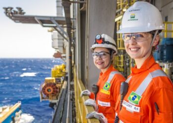 Duas mulheres com uniforme laranja e capacete da Petrobras em plataforma offshore — concurso Petrobras