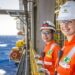Duas mulheres com uniforme laranja e capacete da Petrobras em plataforma offshore — concurso Petrobras
