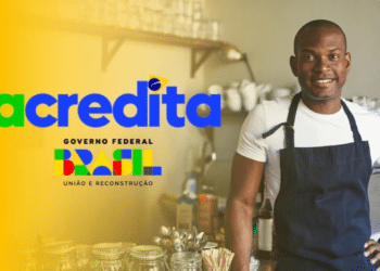 Homem negro sorridente usa avental azul-marinho em cozinha profissional, ao lado da marca do Programa Acredita