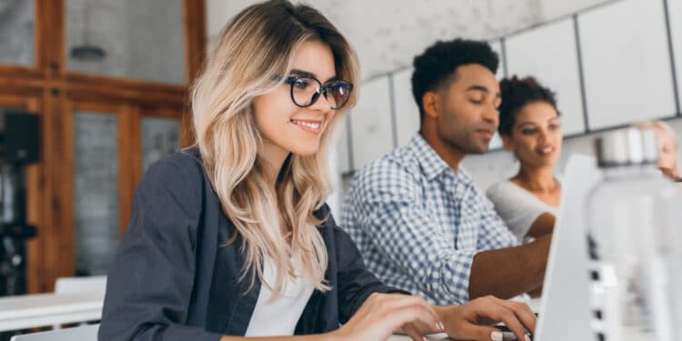 Jovens estagiários trabalhando em notebook no escritório — estagiários podem ganhar salário mínimo com novo projeto de lei 2026