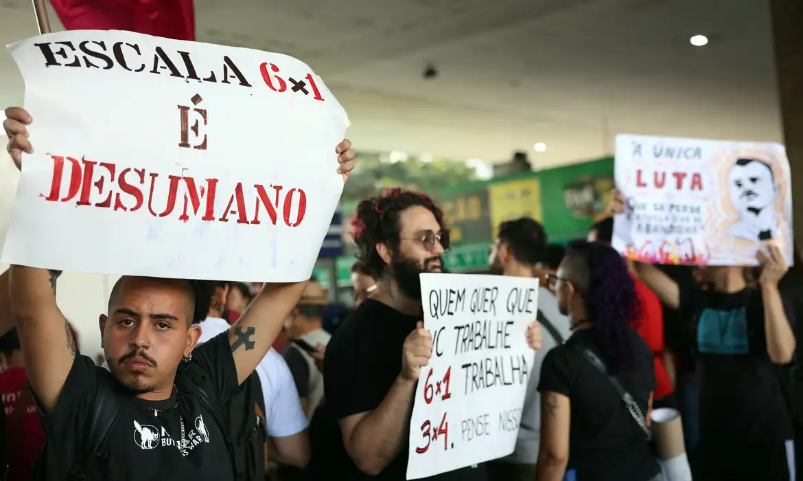 Manifestantes seguram cartazes durante ato contra a escala 6x1 e a favor da redução da jornada de trabalho no Brasil.
