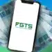 Aplicativo do FGTS exibido em um smartphone com notas de real ao fundo, representando o saque-aniversário disponível aos trabalhadores.