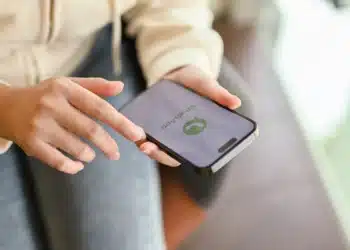 Pessoa segurando smartphone com chamada do WhatsApp, ilustrando risco de exposição de localização durante ligações