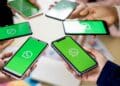 Várias pessoas segurando smartphones com o logo do WhatsApp na tela, representando a possibilidade de usar a mesma conta em múltiplos dispositivos.