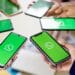 Várias pessoas segurando smartphones com o logo do WhatsApp na tela, representando a possibilidade de usar a mesma conta em múltiplos dispositivos.