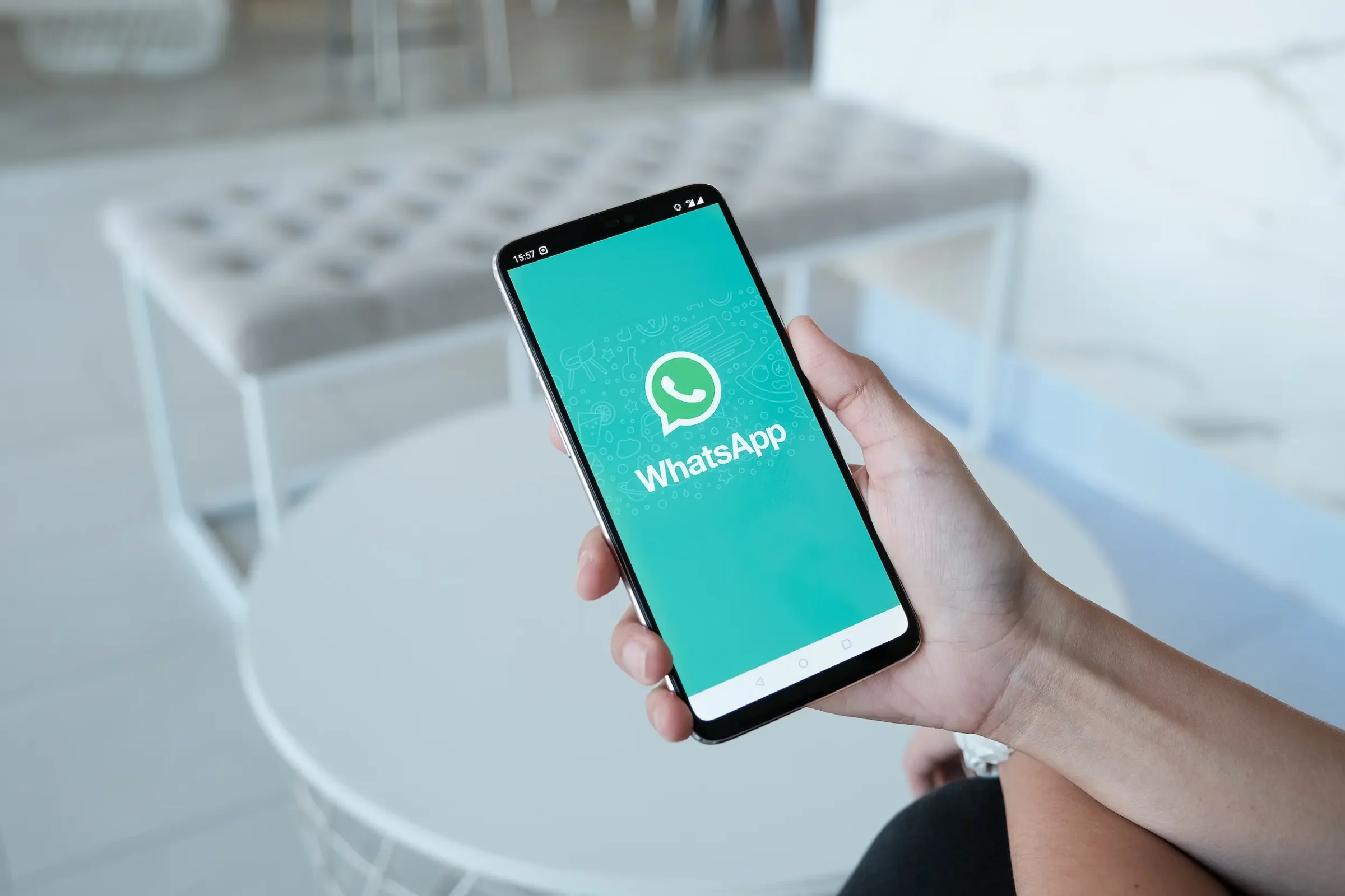 Pessoa segurando celular com WhatsApp aberto, destacando a dificuldade de sair de listas de transmissão.