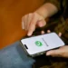 Pessoa utilizando smartphone com WhatsApp aberto representando o novo visual da tela inicial com acesso rápido ao status