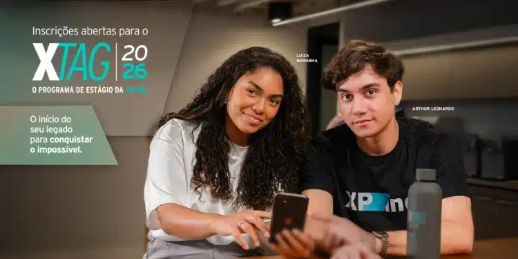 Banner oficial do XTAG 2026, programa de estágio da XP Inc., com dois jovens participantes olhando para a tela do celular em ambiente corporativo