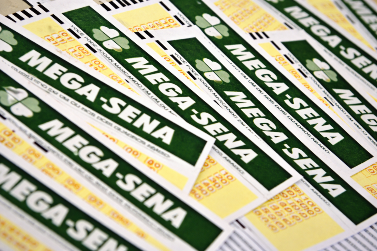 Diversos volantes da Mega-Sena espalhados sobre uma mesa, representando o concurso especial de 30 anos da loteria da Caixa
