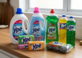 Produtos Ypê incluindo detergente, amaciante, multiuso, sabão em barra e lã de aço dispostos em bancada de madeira.