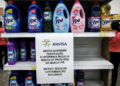 Prateleira de supermercado com frascos da marca Ypê e aviso da Anvisa sobre recolhimento por risco de contaminação.
