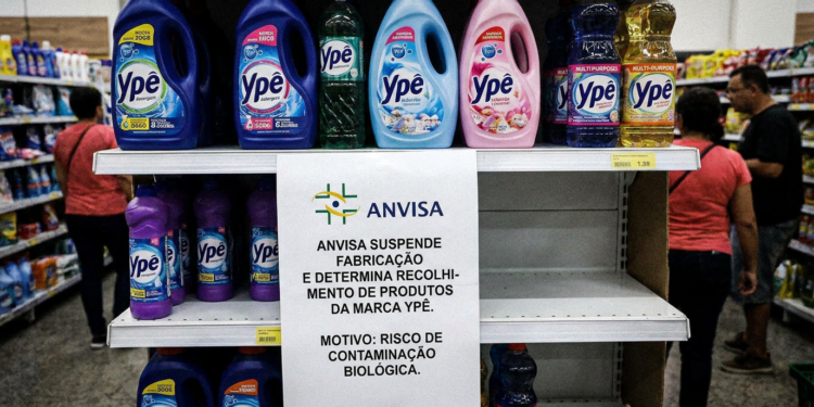 Prateleira de supermercado com frascos da marca Ypê e aviso da Anvisa sobre recolhimento por risco de contaminação.
