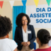 Assistente social Ana Silva sorri ao interagir com grupo em evento decorado com bandeirolas coloridas.