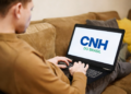 Homem acessa plataforma CNH do Brasil em notebook no sofá.