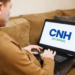 Homem acessa plataforma CNH do Brasil em notebook no sofá.
