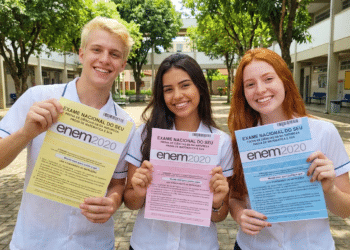 Estudantes exibem provas ENEM 2020 de cores diferentes no pátio escolar.
