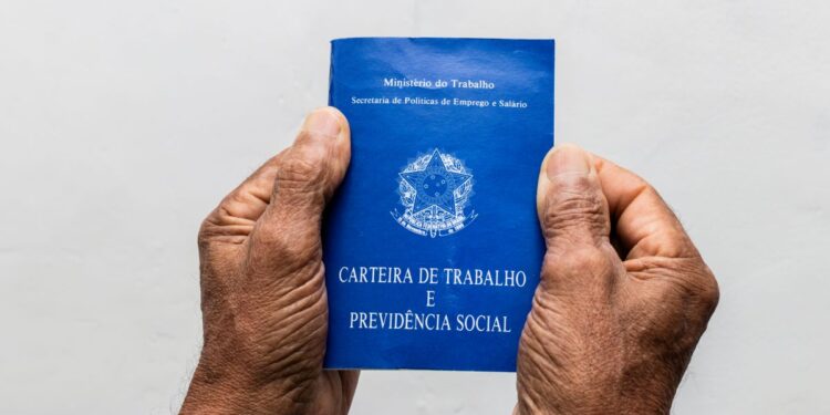 Mãos segurando uma carteira de trabalho.