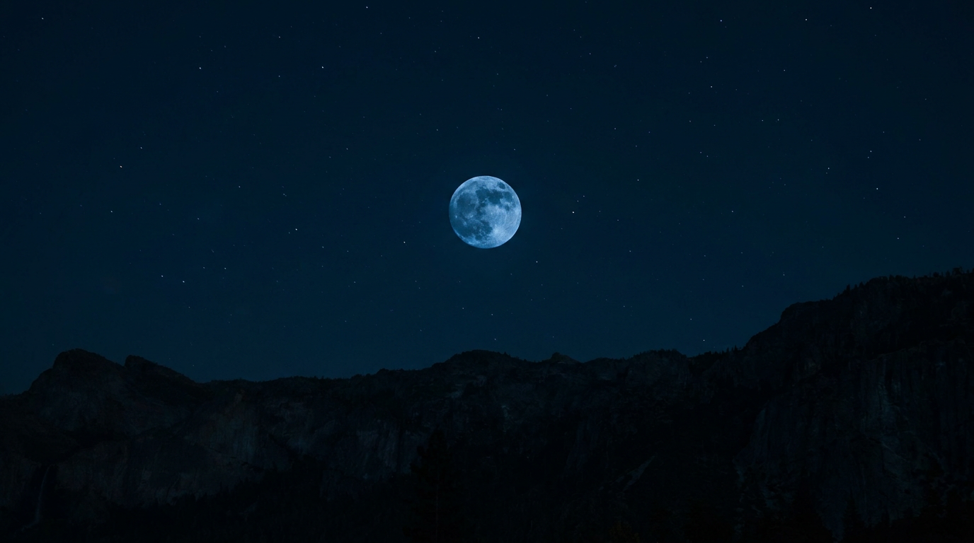 Lua cheia centralizada em céu azul escuro estrelado, com silhueta de montanhas rochosas na base da composição