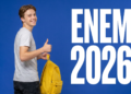 Jovem com camiseta cinza e mochila amarela faz sinal de positivo ao lado do texto ENEM 2026 sobre fundo azul.