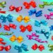 Laços coloridos de cetim em vermelho, azul, verde, rosa, amarelo e laranja sobre fundo azul degradê para teste de observação