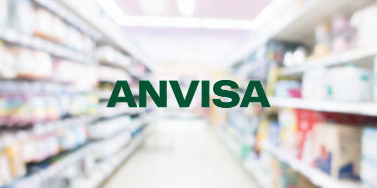 Nome "ANVISA" em corredor de farmácia com prateleiras de medicamentos.