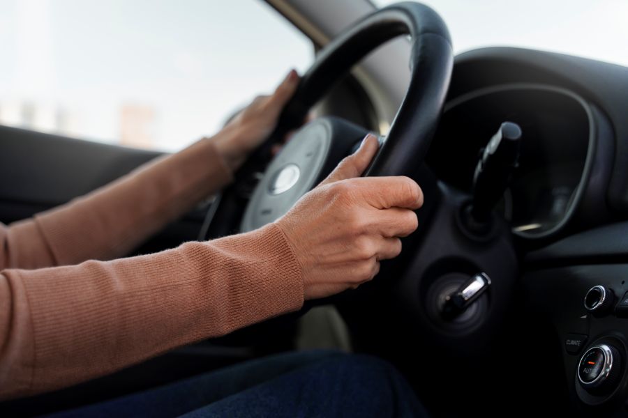 Mãos femininas no volante.