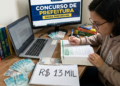 Jovem de óculos estuda apostila em mesa com notebook, monitor exibindo "Concurso de Prefeitura", dinheiro e caderno com "R$ 13 MIL"