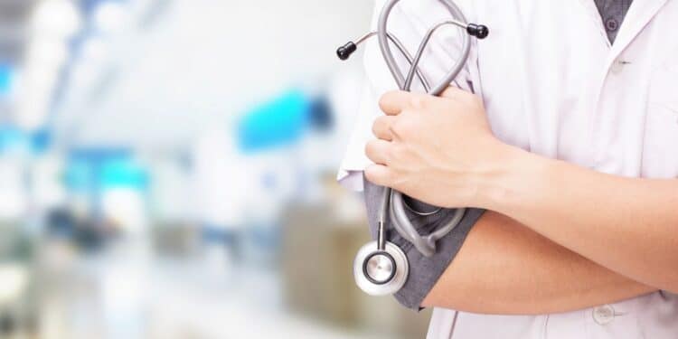 Profissional de saúde com estetoscópio em ambiente hospitalar.