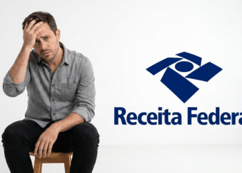 Homem com mão na cabeça, expressão preocupada, sentado em banco ao lado do logotipo da Receita Federal.