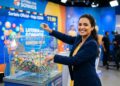 Apresentadora segura bola 33 ao lado de globo com bolas coloridas no sorteio da Loteria dos Sonhos