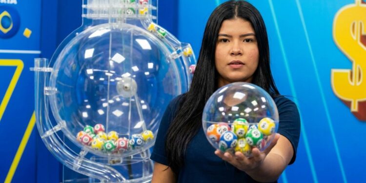 Mulher segura globo transparente com bolas numeradas coloridas em estúdio de loteria azul