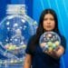 Mulher segura globo transparente com bolas numeradas coloridas em estúdio de loteria azul