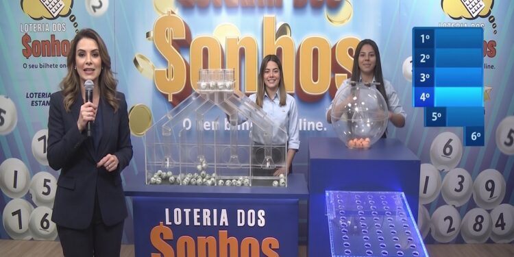 Apresentadora com microfone e duas auxiliares realizam sorteio da Loteria dos Sonhos com globos e bolas